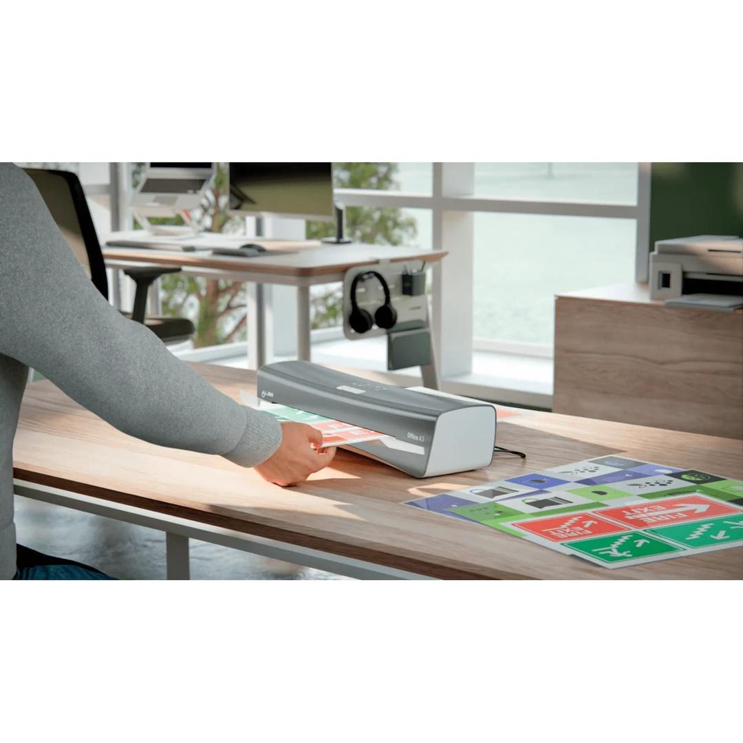 Plastifieuse à pochettes iLAM Office A3 LEITZ - La plastifieuse à pochettes Leitz iLAM Office A3 posée sur un bureau, un document engagé dans la fente