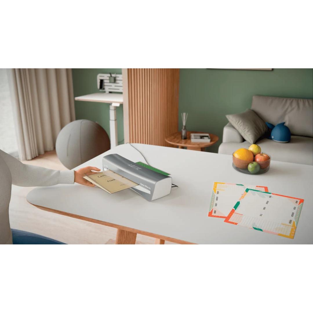 Plastifieuse à pochettes de bureau iLAM Home Office A4 gris LEITZ - La plastifieuse à pochettes Leitz iLAM Home Office A4 posée sur un bureau, un document engagé dans la fente