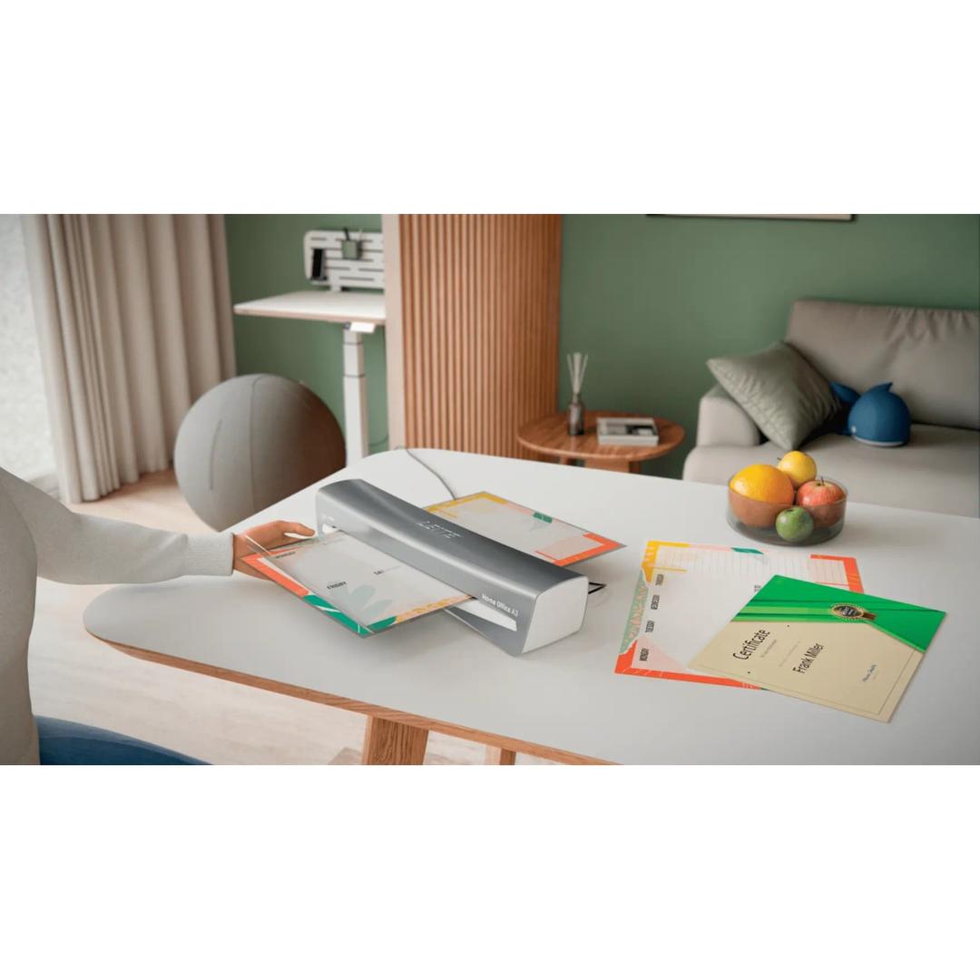 Plastifieuse à pochettes de bureau iLAM Home Office A3 gris LEITZ - La plastifieuse à pochettes Leitz iLAM Home Office A3 posée sur un bureau, un document engagé dans la fente