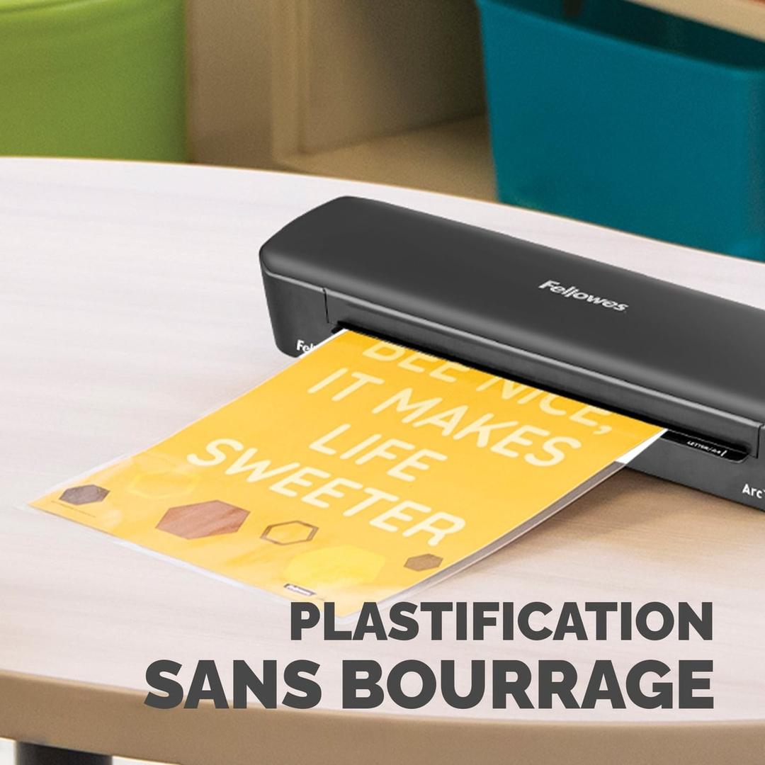 Plastifieuse à pochettes ARC A3 FELLOWES — Machine posée sur une table, une affiche jaune engagée dans la fente