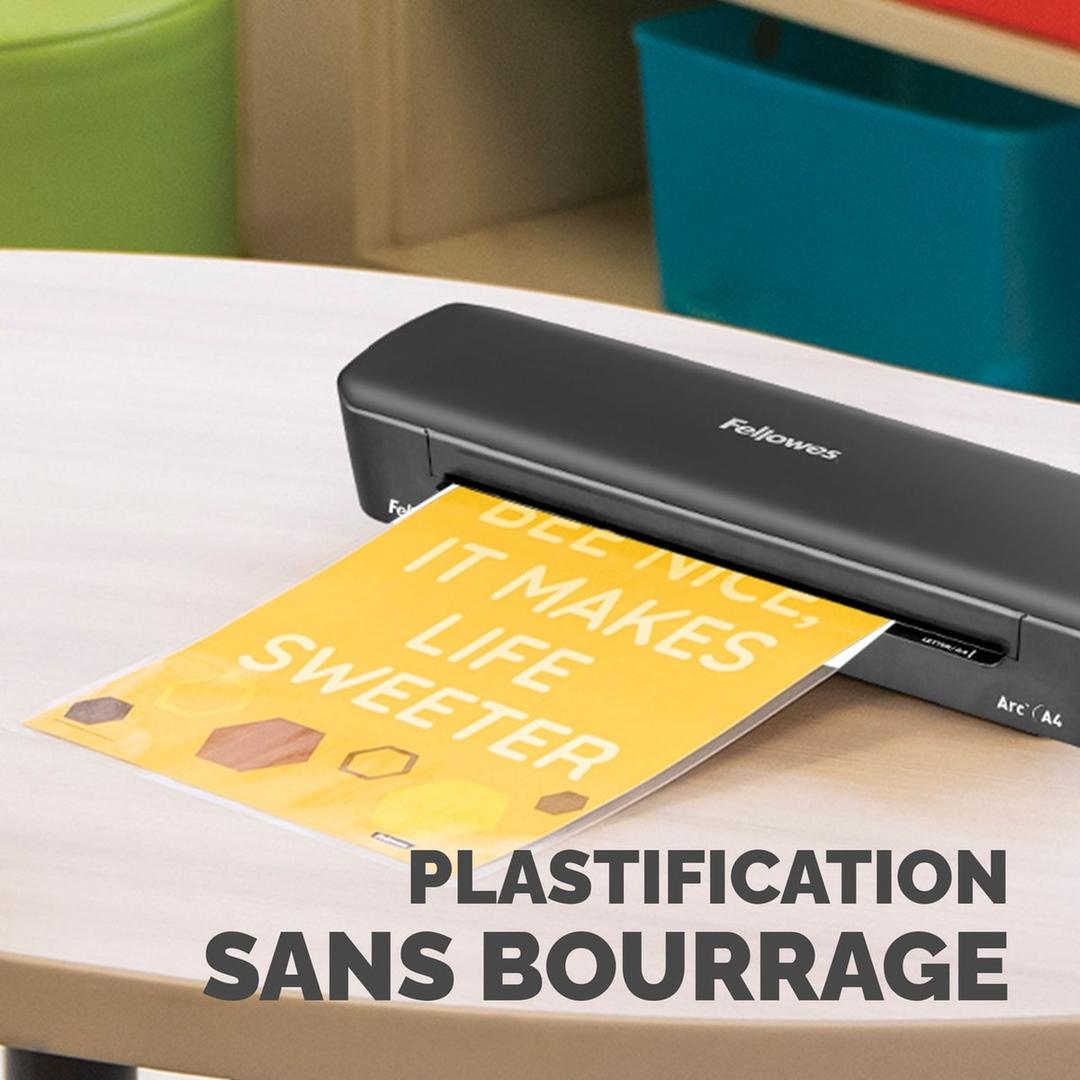 Plastifieuse à pochettes ARC A4 FELLOWES — Machine posée sur une table, une affiche jaune engagée dans la fente