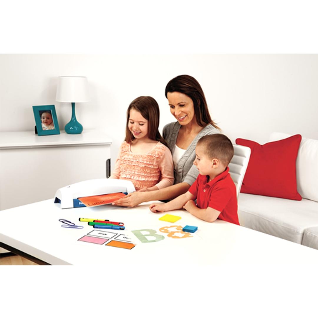 Plastifieuse à pochettes LUNAR+ A4 Bleue FELLOWES - Plastifieuse à pochettes Fellowes Lunar+ A4 sur une table, une mère et ses enfants plastifient des dessins