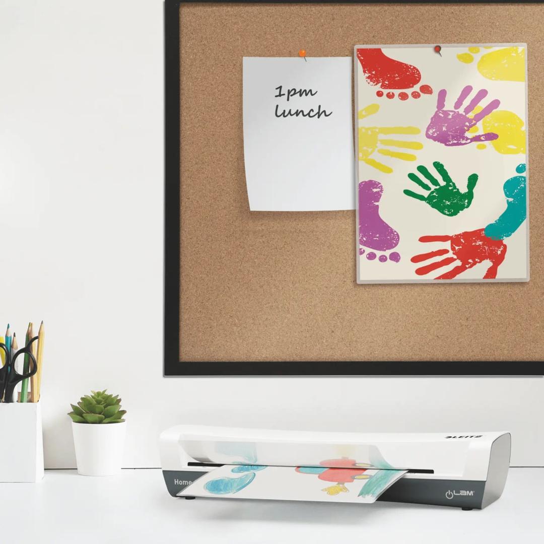 Plastifieuse à pochettes de bureau iLAM Home A3 Blanche LEITZ - La plastifieuse à pochettes Leitz iLAM Home A3 posée sur un bureau, un document engagé dans la fente