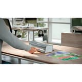 Plastifieuse à pochettes de bureau iLAM Office A4 LEITZ - La plastifieuse à pochettes Leitz iLAM Office A4 posée sur un bureau, un document engagé dans la fente