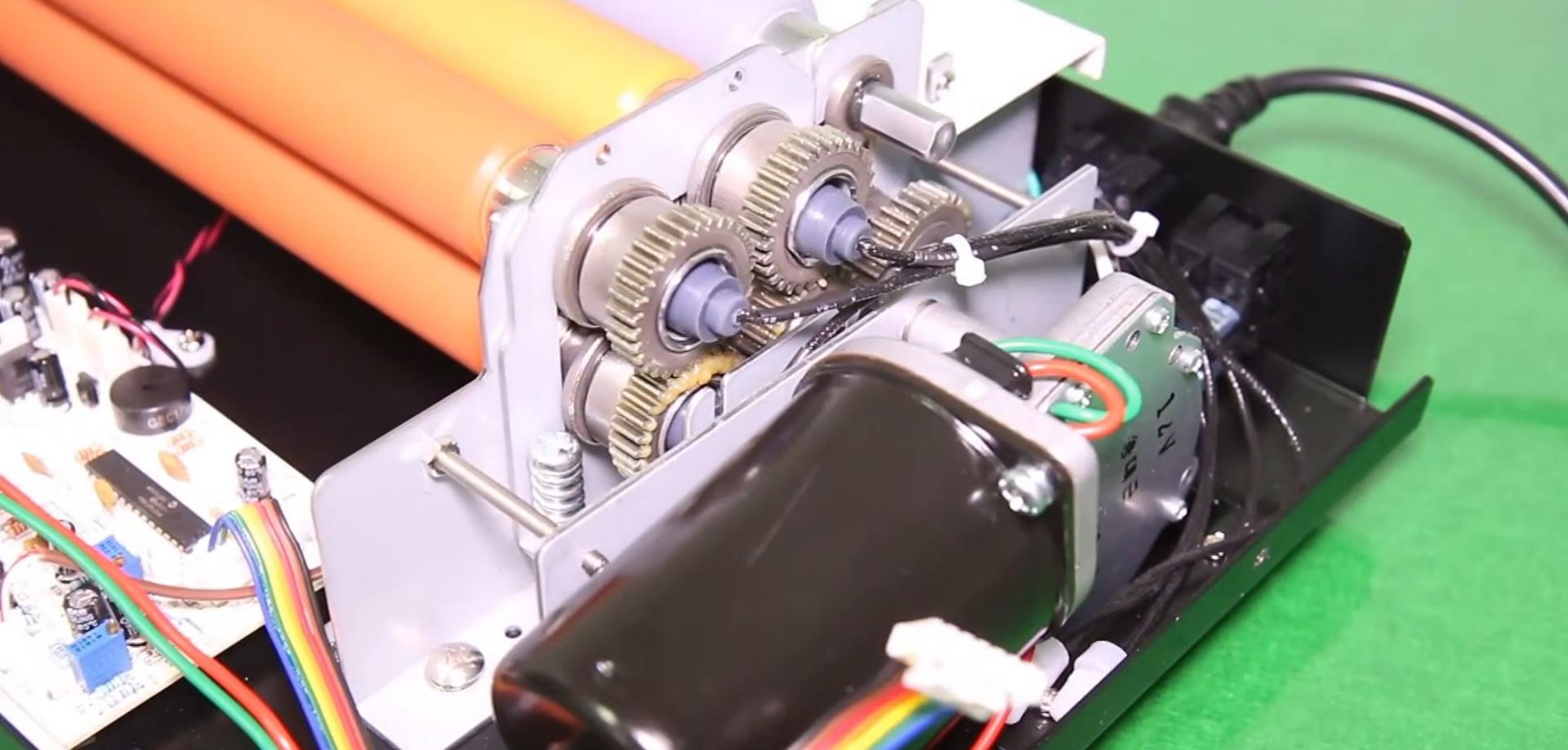 Pignons en métal au bout des rouleaux d'une plastifieuse à pochettes, entraînés par le moteur