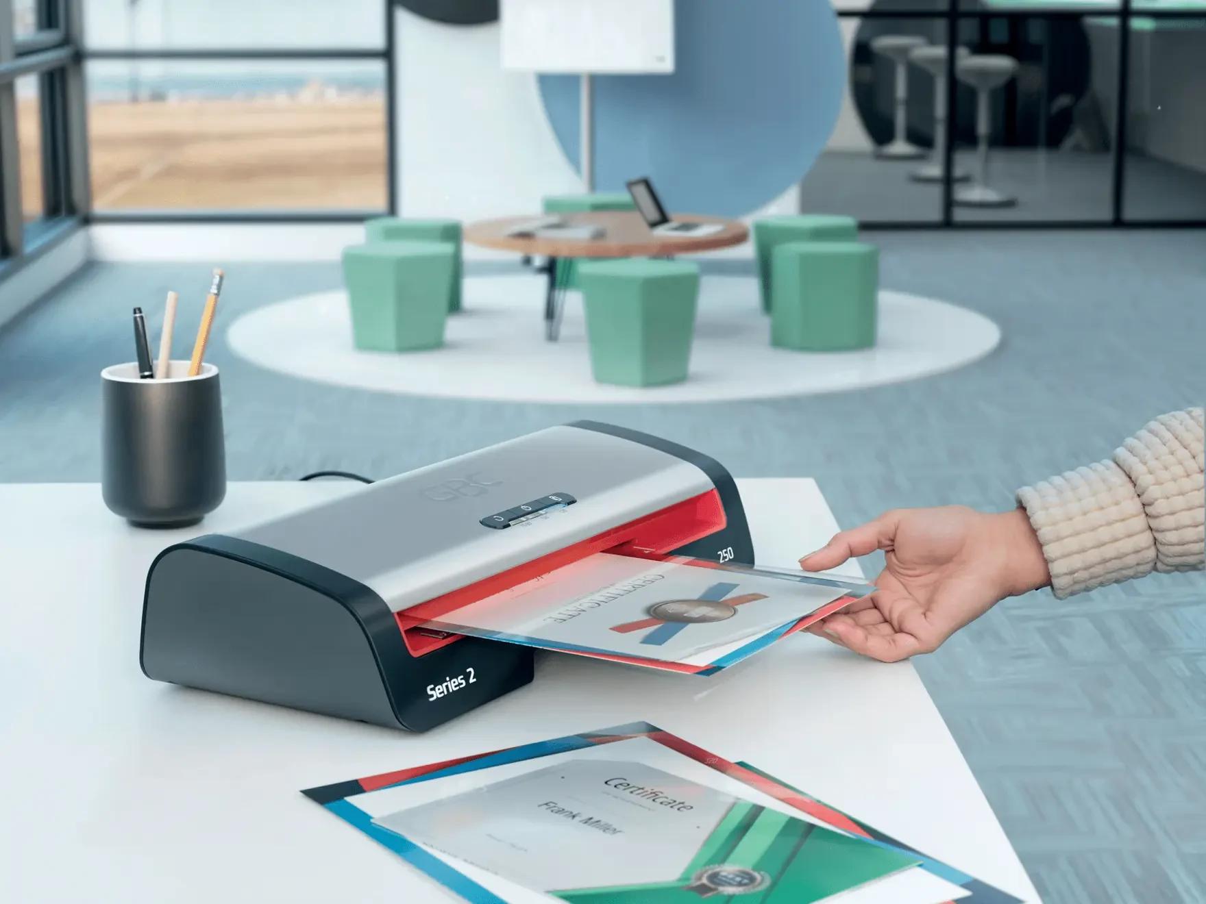 Main glissant un document en pochette dans une plastifieuse de bureau